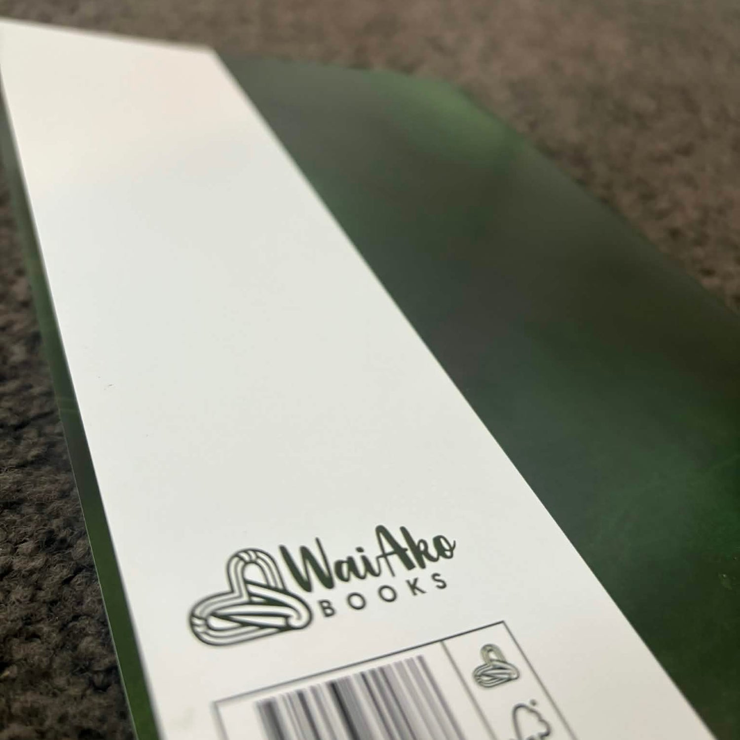 Green book with 'Wai Ako Books' branding on a textured surface