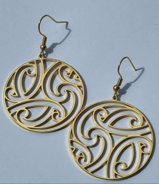 Gold circular earrings with intricate designs on a light blue background